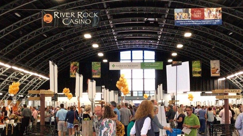 An interior view of the Sonoma County Harvest Fair with tabled vendors and customers moving around.