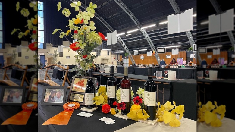 A table at the Sonoma County Harvest Fair has bottles of wine and ribbon laid across it with other decor.