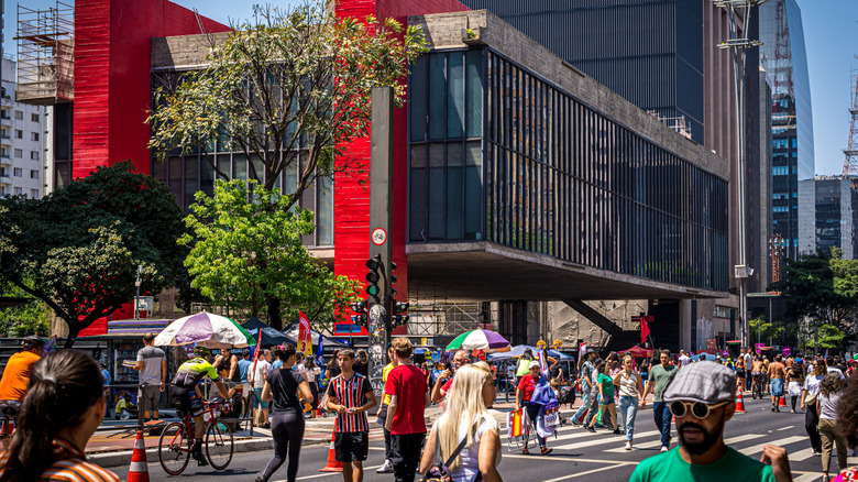 The São Paulo Museum of Art (MASP) boasting a red exterior with people walking in the streets on Avenida Paulista