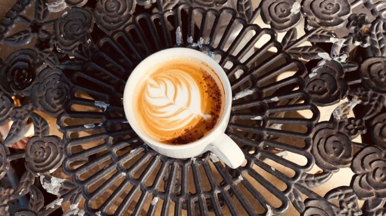 A cup of cappuccino bears a foam-image of a leaf