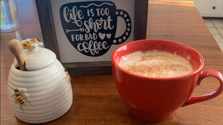 A sign reading "Life is too short for bad coffee" stands next to a mug and honeypot