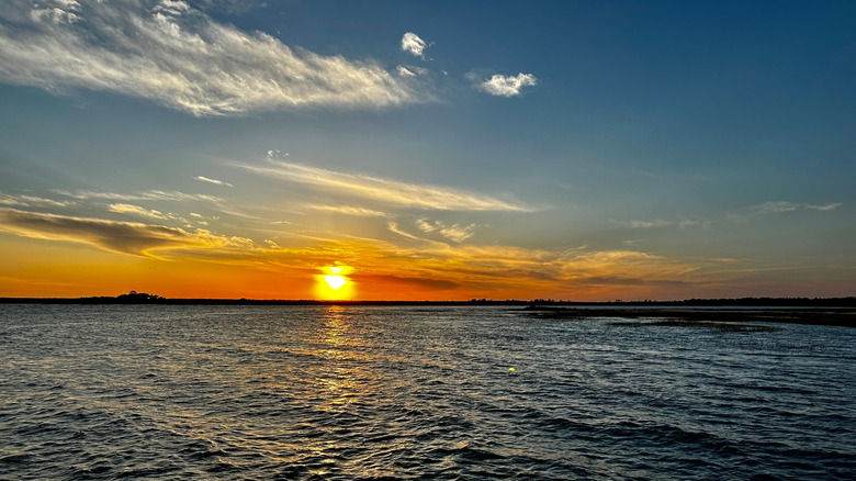 Dark ocean water beneath a blue sky and a yellow sun
