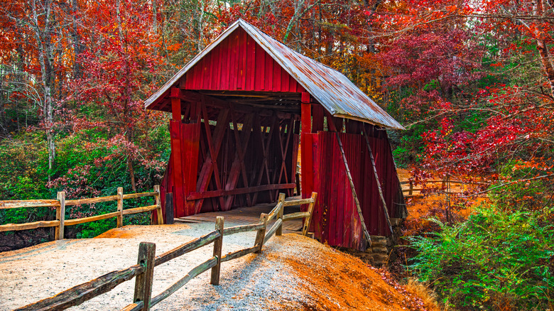 A red wooden covered bridge with fall colors