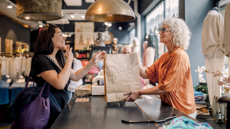 Store owner handing over a paper bag to customer