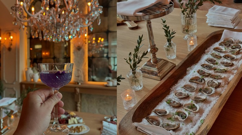 Woman holding wine glass with purple drink and a row of oysters on a decorated table