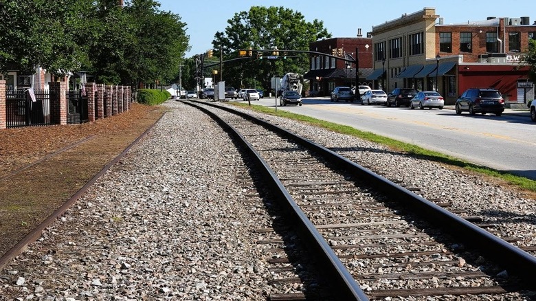 Railroad tracks next to a street with two-story buildings