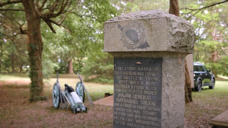 stone marker for Battle of Eutaw Springs with cannon in background