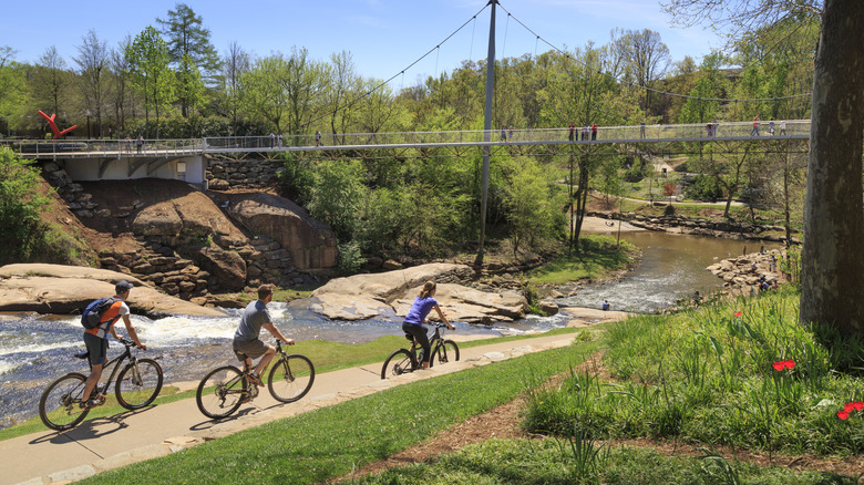 People biking in front of Liberty Bridge at Falls Park on the Reedy