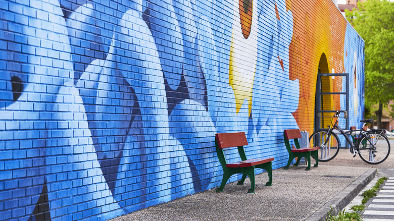 Blue and orange wall mural with red benches and a bicycle