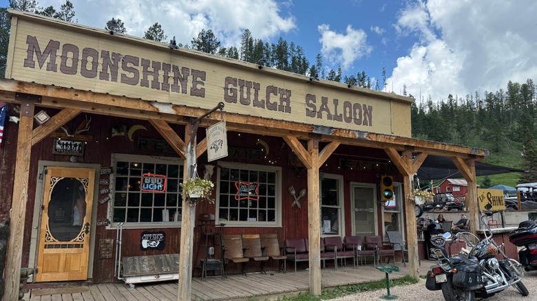 Moonshine Gulch Saloon building with old western sign with blue sky and motorcycle parked out front.