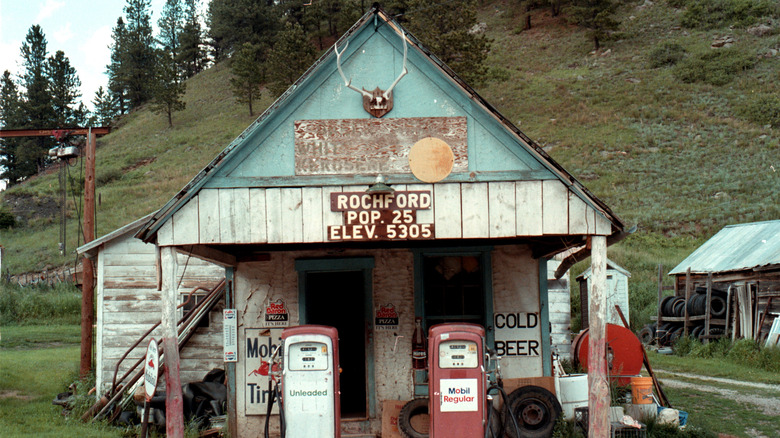 Old wooden gas station up against a hill with Rochford population and elevation sign