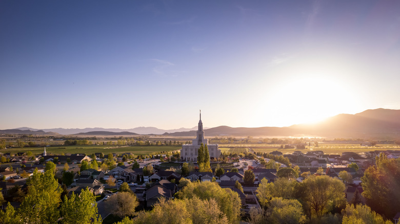 Aerial view of the Payson Utah Temple in the middle of trees and houses on a sunny day under the blue sky
