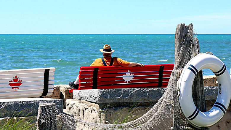 Man with a hat sitting on a bench, enjoying the view of Lake Huron in Southampton, Ontario
