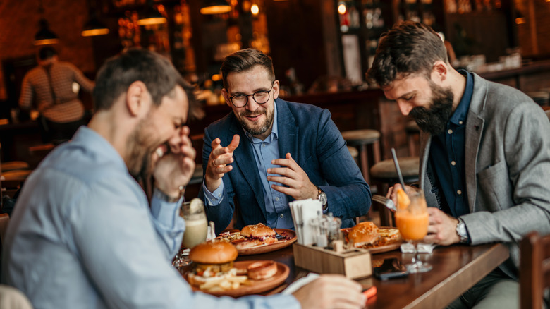 A group of men eating at a restaurant and enjoying each others company