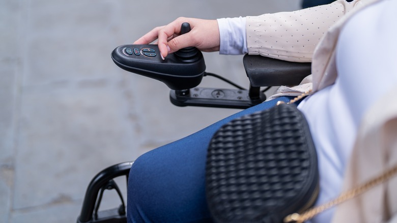 A hand operates a battery-powered wheelchair