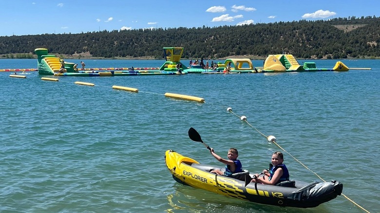Two children using an inflatable kayak in view of the Wibit Aqua Park at Lake Nighthorse