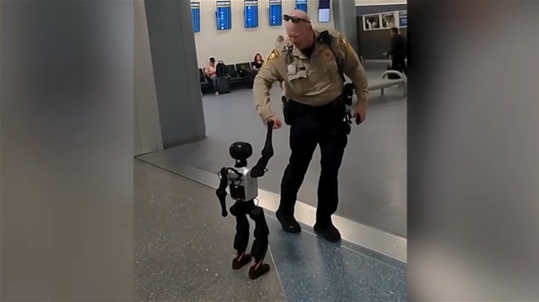 Stewie the robot fist-bumps police officer in airport