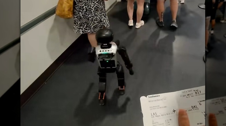 Stewie the robot lines up to board the flight as his owner holds a boarding pass