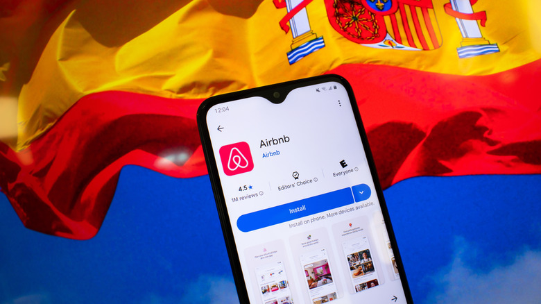 A phone with the Airbnb app in front of the Spanish flag