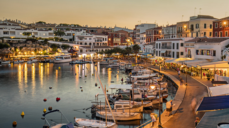 Sunset behind an illuminated Menorca port filled with boats