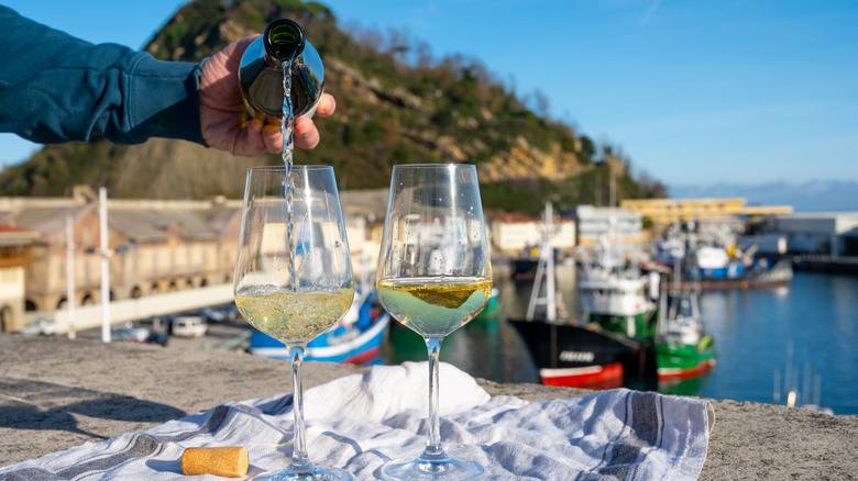 Pouring txakoli with the port of Getaria in the background