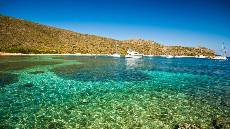 Boats move across the crystal-clear waters of a beach at Cabrera Archipelago Maritime-Terrestrial National Park.