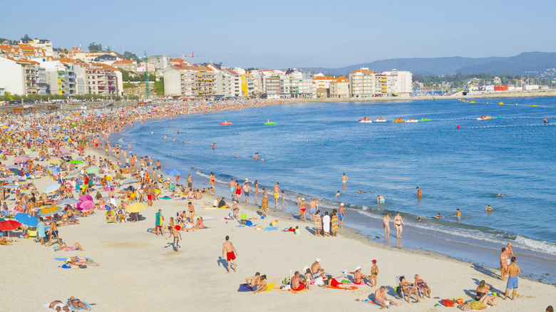 People gathered on a sunny beach in Sanxenxo