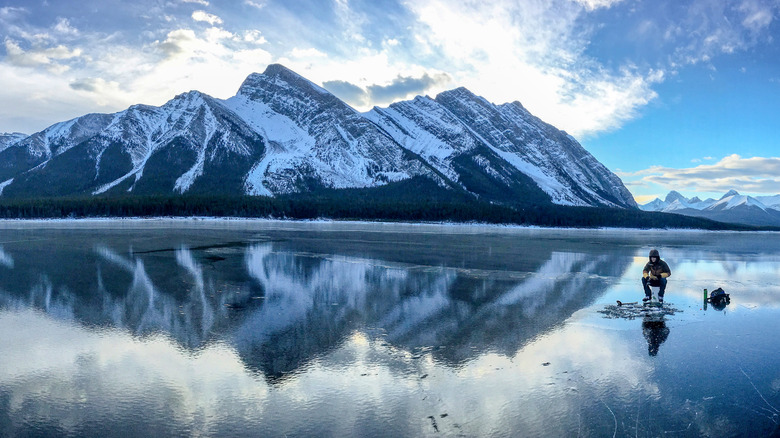 A man ice fishes on a frozen Alberta lake