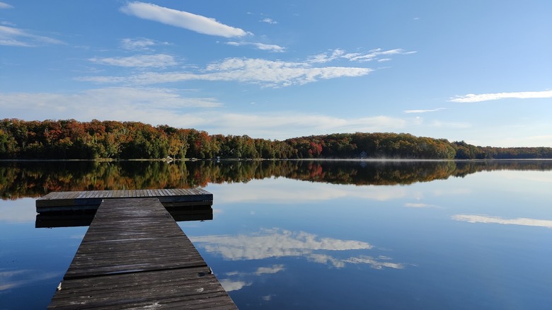 Smooth lake lined by fall trees at Beaver Camp's private dock