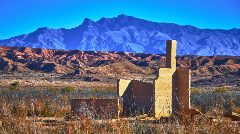 Ruined wall standing against red rock and blue mountains St. Thomas Nevada