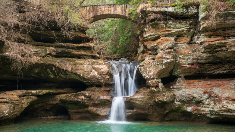 A scenic waterfall under a small stone bridge at the Hocking Hills State Park