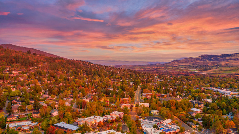 Aerial view of Ashland, Oregon in fall at sunset, with autumn leaves and a pink, peach, and lavender sky