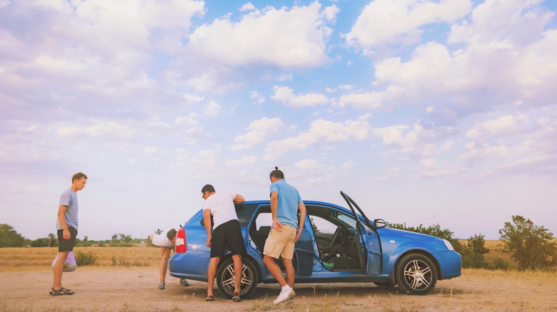 friends looking at broken down car