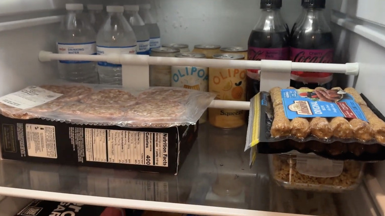 A tension rod bar setup inside of an RV fridge that keeps the food from moving while in motion