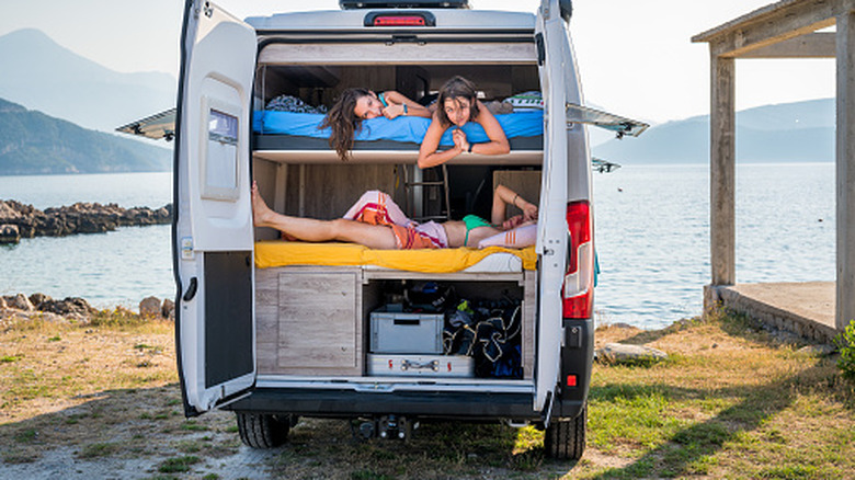 The back of camper van open showing two beds with storage underneath
