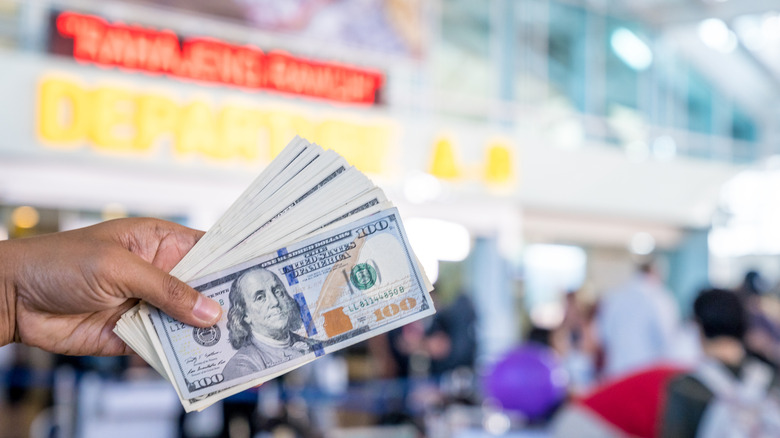 Hand holding cash in an airport