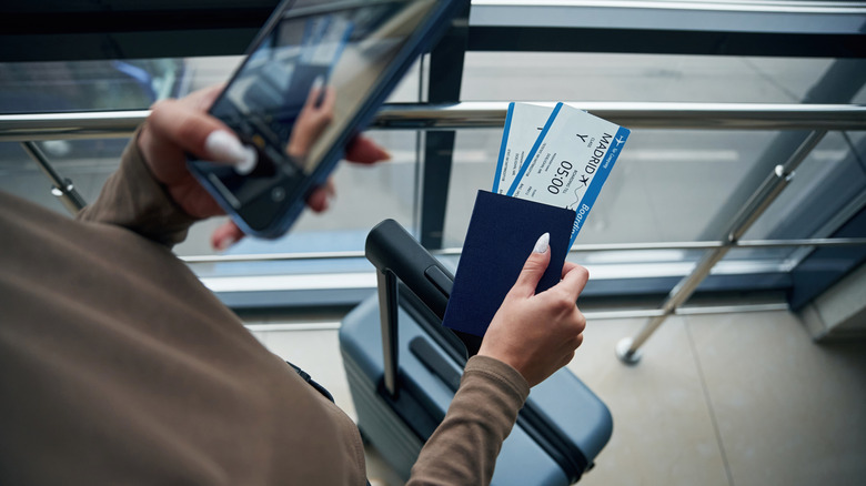 Hand taking photo of plane tickets