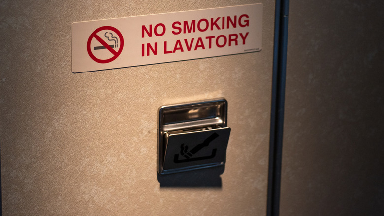 Door of vacant lavatory in airplane with no smoking sign