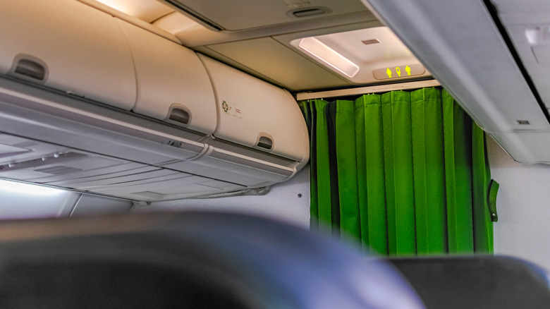 Interior view of a first-class seat aircraft, a green curtain separating the entrance aisle