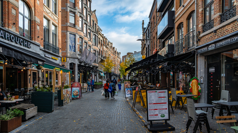 Restaurant tables and chairs lining a cobblestone street in Leuven, Belgium