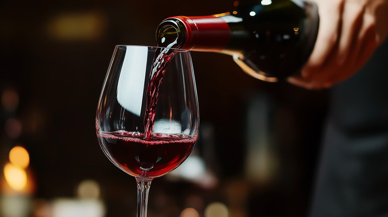 A glass of red wine being poured.