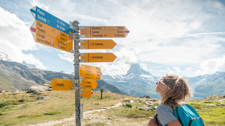 a woman hiking in Switzerland looks at trailhead markings