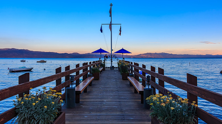 A wooden pier with flowers extends into Lake Tahoe just after dusk.