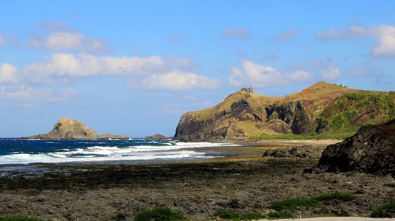 The rocky coastline and beach at Nioutoushan in Ludao, Taiwan, with blue, white-capped waves and a pale sky