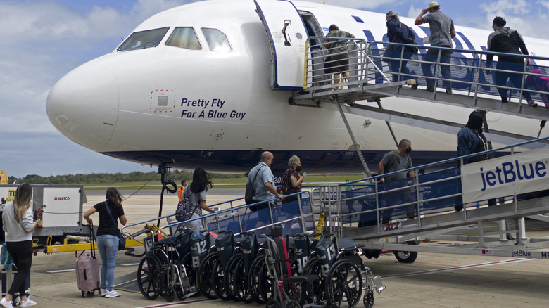 wheelchairs on the tarmac beside a JetBlue plane