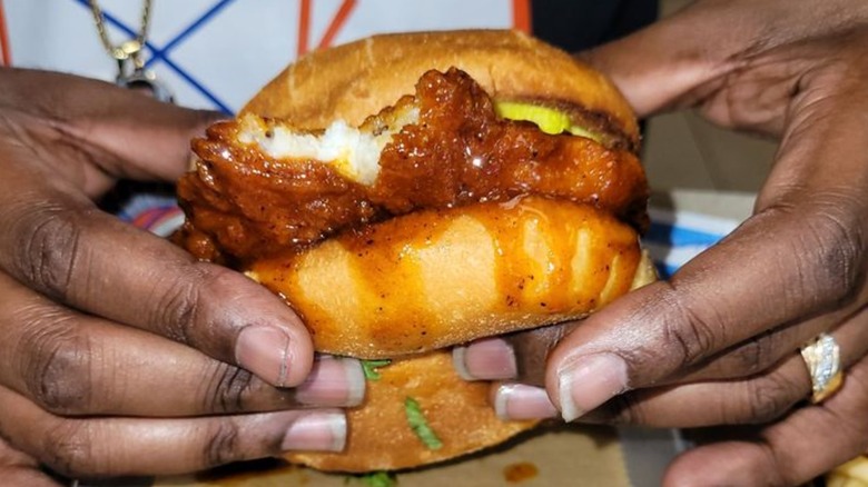 Closeup of hands holding a Nashville hot catfish sandwich, a Half Moon Seafood Company signature in Tampa