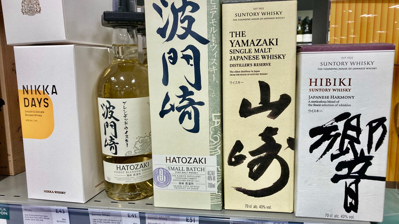 A row of Japanese whiskies stand lined up in a liquor store