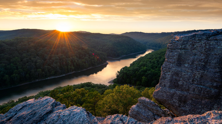 Sun shines over Big South Fork River lined with trees and cliffs