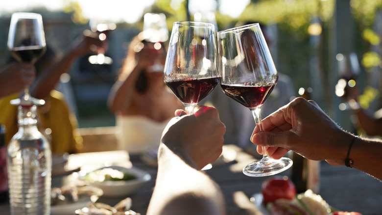 People surrounding a table clinking wine glasses