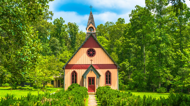 1880s wooden church with a bell tower, surrounded by trees